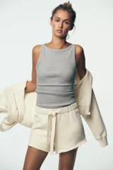Shorts color crudo de tiro medio con cintura elástica ajustable con cordones y bajo desflecado.