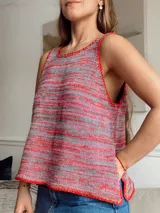 Chaleco de punto con rayas horizontales en tonos rojo, gris y rosa. Tiene cuello redondo y ribete rojo en cuello, sisas y bajo. Corte holgado con aberturas laterales.