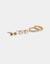 Set de tres pares de aros dorados: un par de aros tipo botón con bolitas, un par de aros tipo botón con circonitas y un par de aros argolla con circonitas.