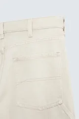 Pantalón gris de corte relaxed fit, con cinco bolsillos, efecto lavado, aplicación de tira y bolsillo multifunción en perneras. Cierre frontal con cremallera y botón.