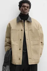 Parka negra de algodón con cuello solapa de cuero sintético, corte recto, acolchada, con bolsillos de parche y cierre frontal con botones.