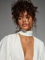 Vestido corto blanco de manga globo con cuello cruzado profundo en V, volantes y efecto drapeado.