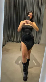 Vestido corto negro strapless con brillos y corte asimétrico.