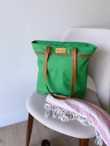 Bolso de lona color negro con detalles en cuero marrón, con bolsillo interno y forro de tela.