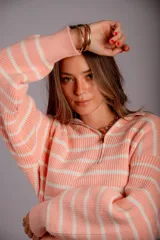 Sweater de punto color beige con rayas horizontales blancas, cuello polo con cierre de cremallera y mangas largas.