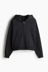 Campera con capucha en felpa de algodón pesado, color negro, con cierre y bolsillos delanteros, hombros caídos y corte oversized.