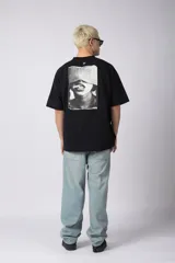 Remera negra oversize de algodón premium con cuello redondo y mangas cortas. Presenta un logo bordado en el frente y un parche estampado en la espalda.