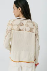 Cárdigan azul con detalles en crochet, mangas con volado y vivos de color rojo en cuello, puños y frente. Tiene botones al frente.