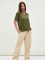 Remera negra de corte holgado con cuello en V y apliques de tachas doradas en los hombros.