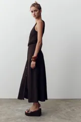 Vestido midi color marrón oscuro, sin mangas, con escote cuadrado, detalle de botones frontales y cinturón elástico con hebilla dorada.