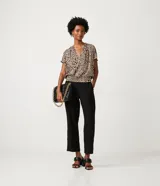 Blusa de crepé color beige con estampado de leopardo, escote en V, manga corta y bajo elástico.
