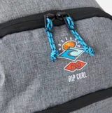 Mochila Rip Curl modelo Ozone de 30 litros, color gris jaspeado con detalles en negro. Presenta un compartimento principal amplio, un bolsillo frontal con cierre y un logo de Rip Curl con diseño de sol y olas.