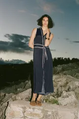 Vestido midi azul marino con estampado de lunares blancos, cuello solapa, escote en pico y sin mangas. Incluye cinturón de la misma tela y cierre frontal con botones.