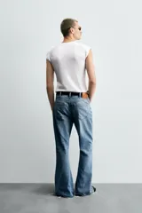 Pantalón de jean celeste, de tiro medio, corte ajustado en la parte superior y acampanado desde la rodilla. Tiene cinco bolsillos, efecto lavado y bajo irregular.