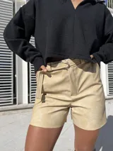 Short color beige de ecocuero con cinturón con hebilla plateada.