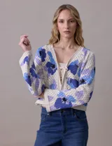 Cárdigan tejido calado color beige con estampado floral en tonos de azul y lila. Escote en V y cierre frontal con lazo.