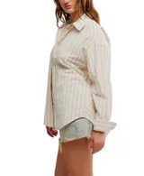 Camisa a rayas verticales color crema y marrón, de corte oversize y estilo masculino. Tiene cuello camisero, cierre frontal con botones y canesú en la espalda.