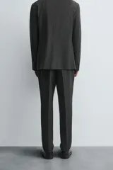 Pantalón de vestir de corte slim fit, color gris oscuro con micro estampado a cuadros. Cuenta con bolsillos laterales y traseros de doble vivo con botón. Cierre frontal con cremallera y botón.