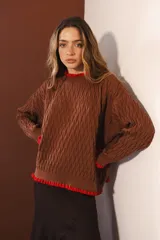 Sweater tejido rojo con cuello alto y puños con volados azules.