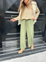 Pantalón verde de seda opaca, corte ancho y fluido, tiro medio alto y elástico en la cintura.