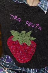 Sweater tejido de lana merino color negro, con cuello a la base y puños. Presenta un bordado artesanal de una frutilla en el frente.