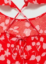 Vestido largo rojo con estampado floral rosa, escote redondo, tirantes finos cruzados en la espalda y corte recto.