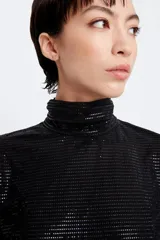 Polera negra de tul con brillos, cuello alto con tablas, mangas largas con frunces en la copa y calce slim.