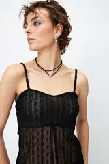 Top blanco de encaje con breteles finos, corte en la cintura y abertura frontal.