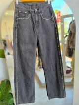 Pantalón de jean gris oscuro con corte recto y detalles de tachas plateadas en los laterales.