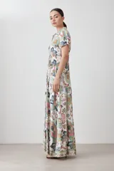 Vestido camisero largo de corte recto, con estampado de arabescos en tonos verde agua, rosa, marrón y gris. Tiene cuello camisero, mangas cortas y cierre frontal con botones.