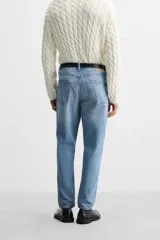 Pantalón de jean celeste de corte slim fit y tapered, con cinco bolsillos, efecto lavado y cierre frontal con cremallera y botón.
