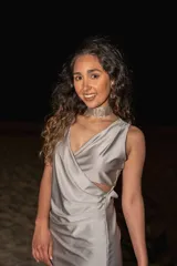 Vestido corto dorado con escote cruzado, sin mangas y abertura en la cintura.