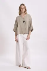 Blusa color beige de lino con corte holgado, mangas 3/4 y cierre con botón grande.