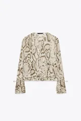Blusa de viscosa con estampado de piel de serpiente en tonos beige y marrón. Tiene cuello redondo con lazo ajustable, mangas largas acampanadas con cordones en los puños y bajo recto.