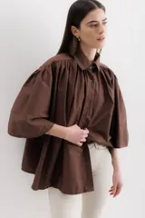 Camisa marrón con cuello clásico, abotonada al frente y mangas 3/4 abullonadas.