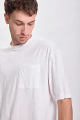 Remera blanca de corte recto, con cuello redondo y bolsillo en el pecho.