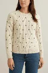 Sweater crudo de lana merino con cuello redondo y bordados de corazones marrones.