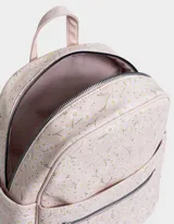 Mochila negra con estampado de margaritas blancas, confeccionada en cuero sintético. Cuenta con correas regulables, manija superior, acceso con cierre, bolsillo frontal con cierre y tag de cuerina. Incluye un pouch extraíble.