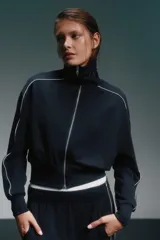 Conjunto deportivo azul marino con detalles de ribete blanco. Incluye una campera corta con cierre y un pantalón de corte recto.