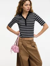 Top ajustado al cuerpo con cuello tipo polo, a rayas horizontales blancas y negras, con botones en el escote y mangas cortas.