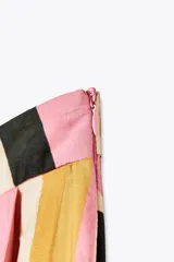 Falda midi de tiro alto confeccionada en hilatura de algodón con estampado geométrico multicolor. Tiene detalle de pliegues en la cintura y bajo evasé.