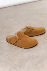 Zuecos de cuero color beige, con diseño clásico y hebilla regulable. Cuentan con plantilla anatómica y suela de corcho.