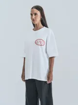 Remera blanca de corte holgado con estampado de dragones en círculo con texto 'No Art Uruguay' y 'Castillo de Piria'.