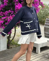 Cárdigan de punto azul marino con diseño náutico bordado en la espalda: un velero blanco y rojo sobre olas blancas, y la inscripción "le port" en blanco.