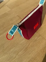 Neceser color beige de forma rectangular, con cierre superior y asa de mano.