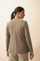 Chaqueta corta color beige, entallada, con escote en V, manga larga y cierre frontal con lazo fijo. Confeccionada en lana fina sin teñir, con bolsillos escondidos y terminaciones enviadas. Hecha 100% en Uruguay.