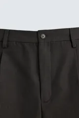 Pantalón de vestir negro de corte recto, con cintura elástica, pliegues frontales, bolsillos laterales y traseros.