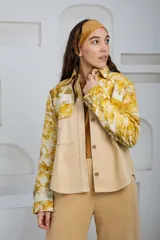 Chaqueta color beige con estampado abstracto en tonos amarillos, con cuello camisero, cierre frontal con botones, bolsillos plaqué y puños camiseros.