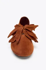 Zapato plano tipo bailarina color marrón de cuero gamuzado, con detalle de flor fantasía en la parte delantera y punta redonda.