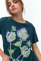 Remera lila de algodón con estampado de flores en tonos naranja y rosa.